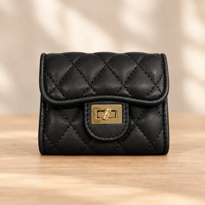 Black quilted wallet with gold clasp on a warm wooden table