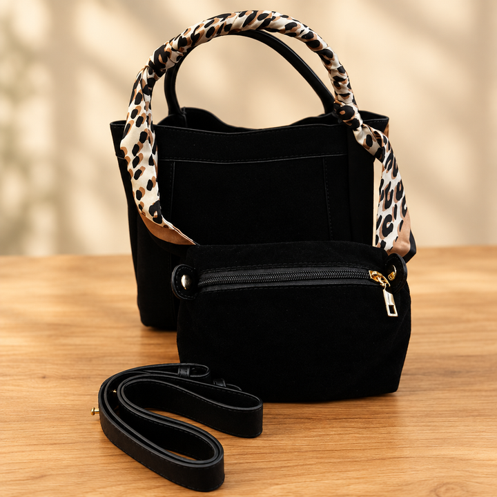Black handbag set with animal-print scarf, matching pouch and strap on a warm wooden table against a soft neutral background