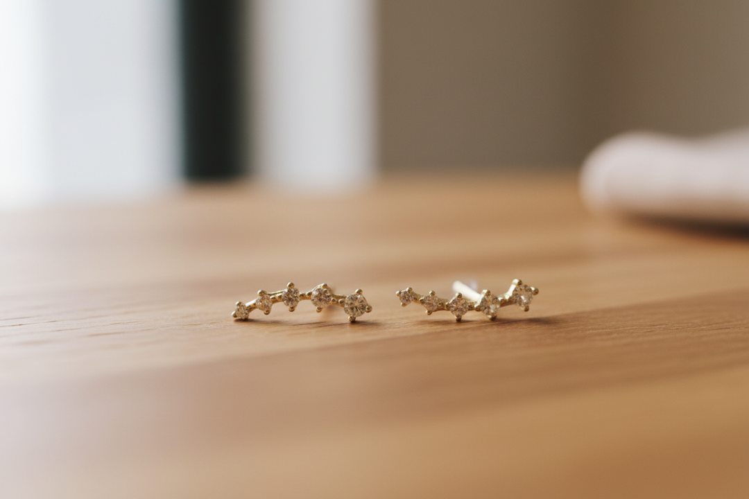 Gold crystal ear crawler earrings on wooden table with soft neutral background
