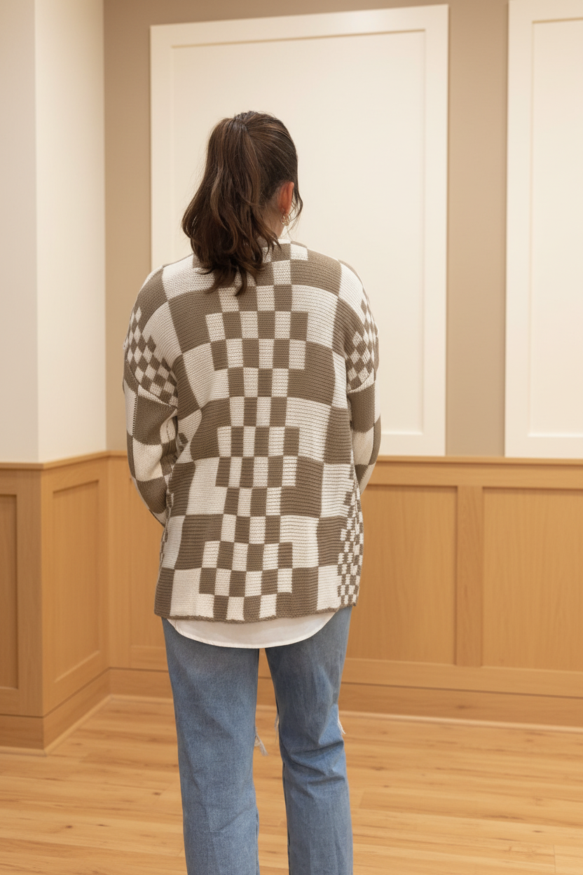 Model wearing a taupe and ivory mixed checkered open-front cardigan in a warm neutral boutique setting, back view