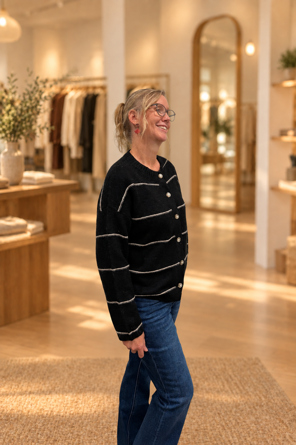 Side view of black thin-striped button cardigan modeled in a warm boutique