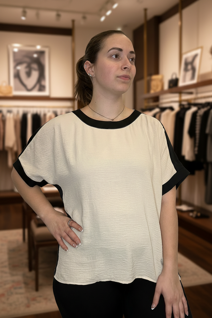 Cream and black colorblock dolman sleeve top front view with blurred boutique background