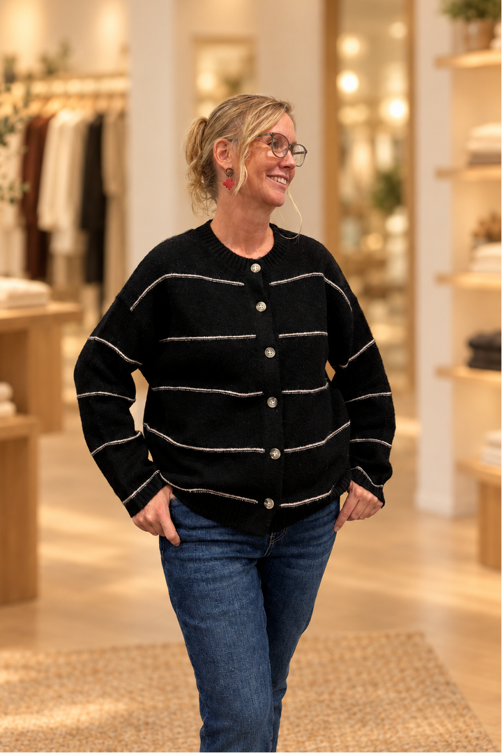 Front view of black thin-striped button cardigan modeled in a warm boutique