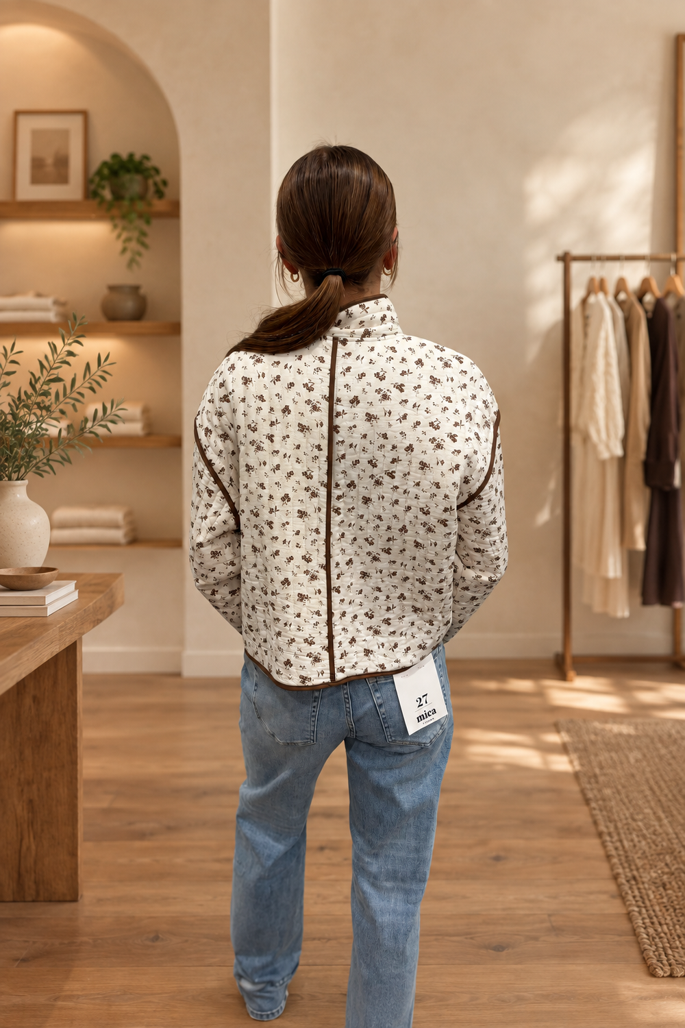 Back view of floral print quilted jacket in warm boutique setting