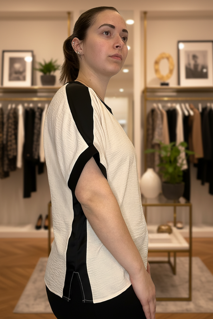 Cream and black colorblock dolman sleeve top alternate front view with blurred boutique background