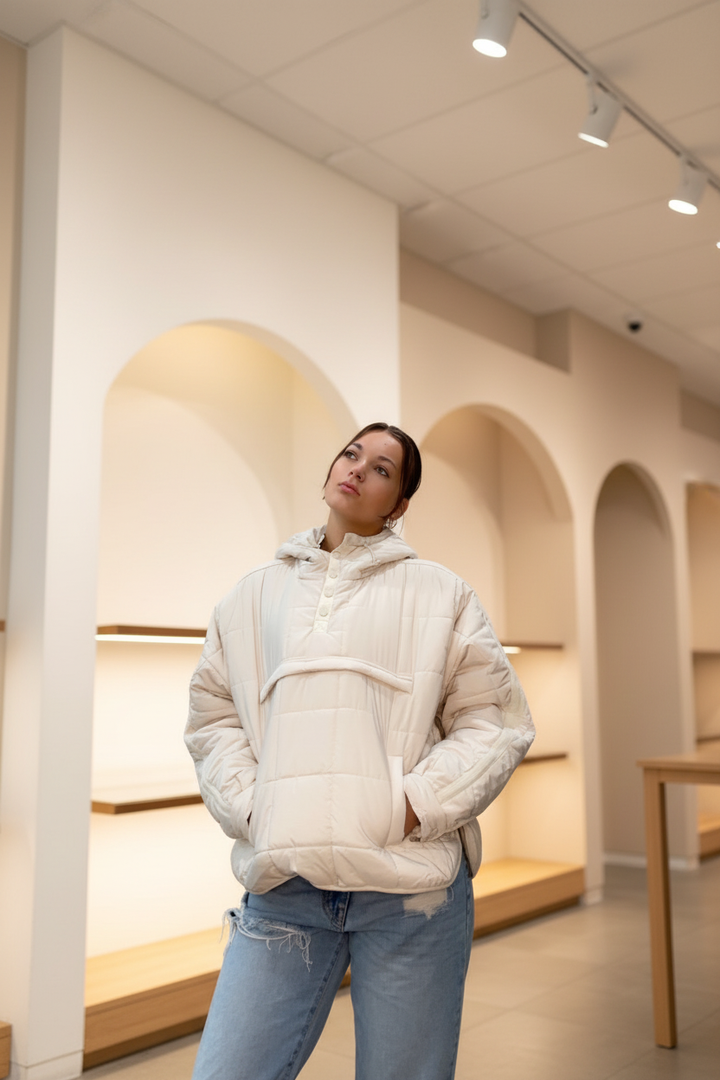 Model wearing a cream quilted jacket in a warm neutral boutique setting, front view