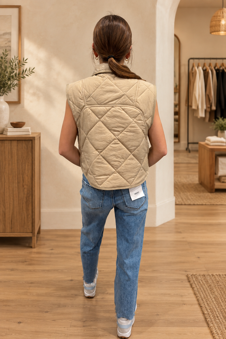 Back view of cream quilted vest showing diamond stitching in a warm boutique setting
