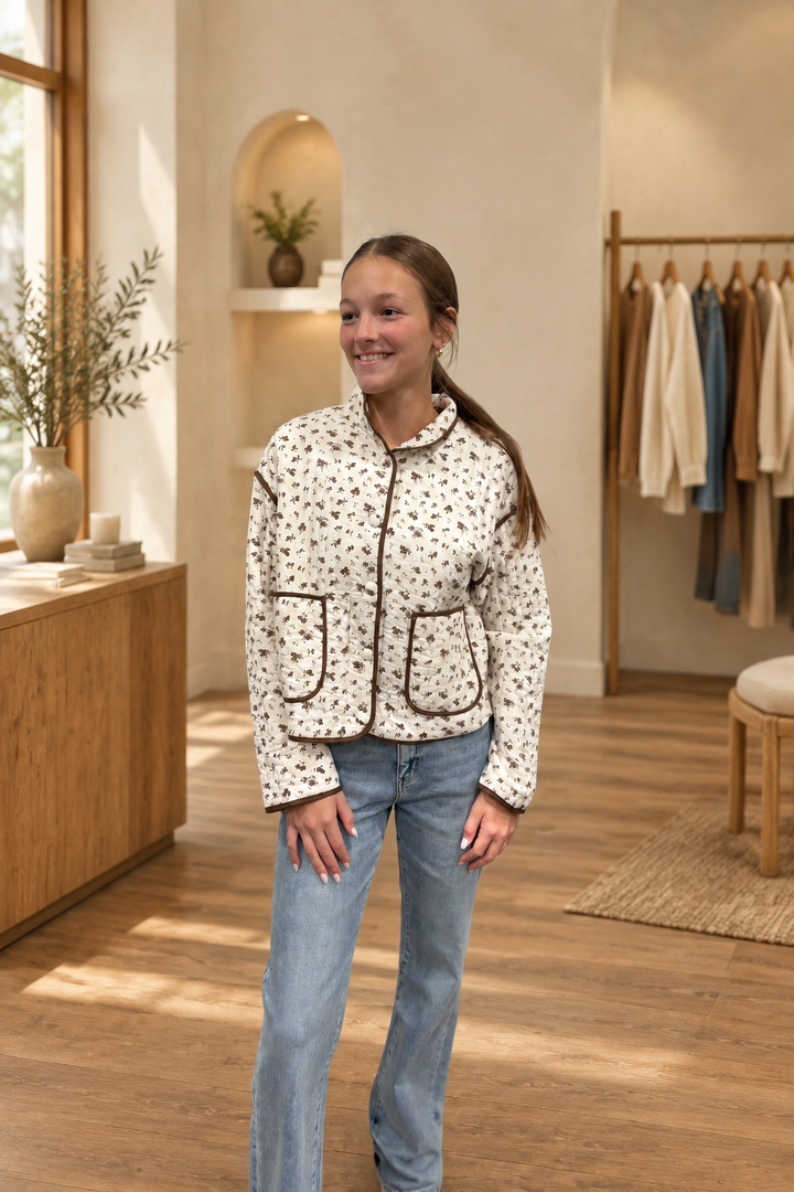 Front view of floral print quilted jacket in warm boutique setting